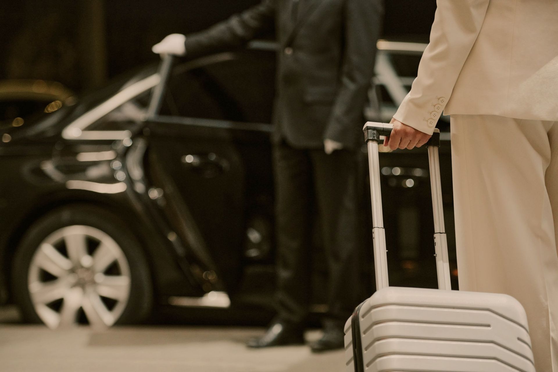 Traveller with a suitcase beside a chauffeured car
